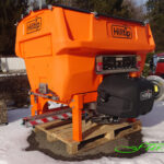 HILLTIP IceStriker 600TR in der Farboption Kommunal-Orange ausgestattet mit der Feuchtsalz-Vorbfeuchterbaugruppe, dem Solesprühbalken sowie dem Handsprühsystem sowie Kennzeichenbeleuchtungskit sowie Arbeitsscheinwerfer; geeignet für alle Traktoren und Zugmaschinen mit Dreipunktaufnahmen der Kategorien I, II und 0