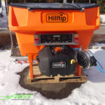 HILLTIP IceStriker 600TR in der Farboption Kommunal-Orange ausgestattet mit der Feuchtsalz-Vorbfeuchterbaugruppe, dem Solesprühbalken sowie dem Handsprühsystem sowie Kennzeichenbeleuchtungskit sowie Arbeitsscheinwerfer; geeignet für alle Traktoren und Zugmaschinen mit Dreipunktaufnahmen der Kategorien I, II und 0